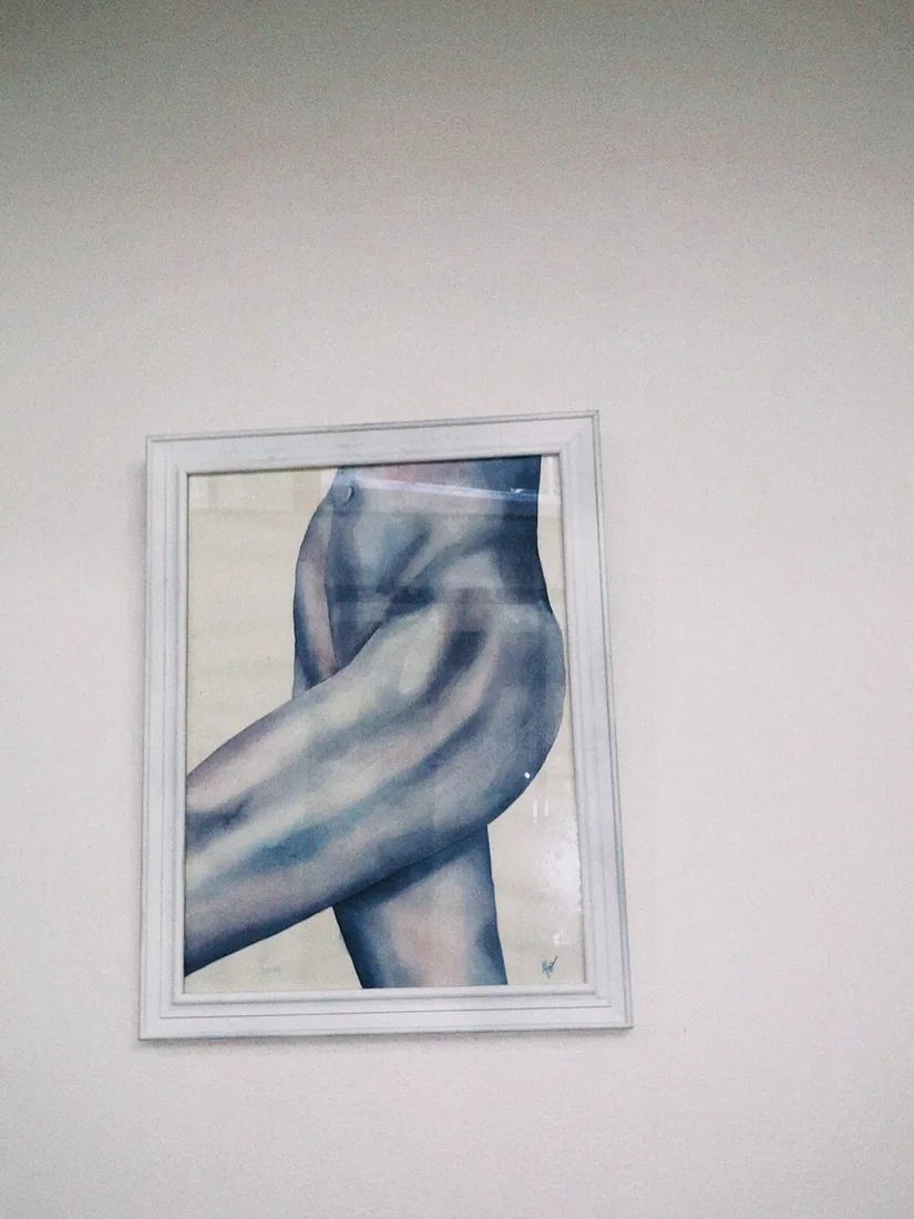 Una acuarela de un torso, enmarcada en blanco sobre una pared.