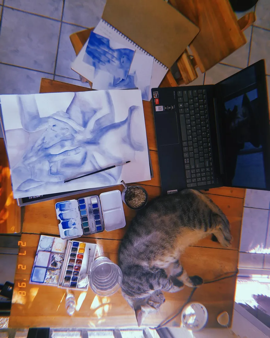 Mi mesa de trabajo: una acuarela azul a medio hacer, la paleta y mi gata dormida al lado.