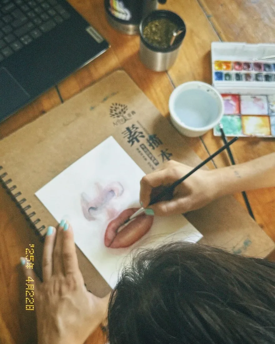 Pintando unos labios en acuarela, con el pincel sobre el papel.